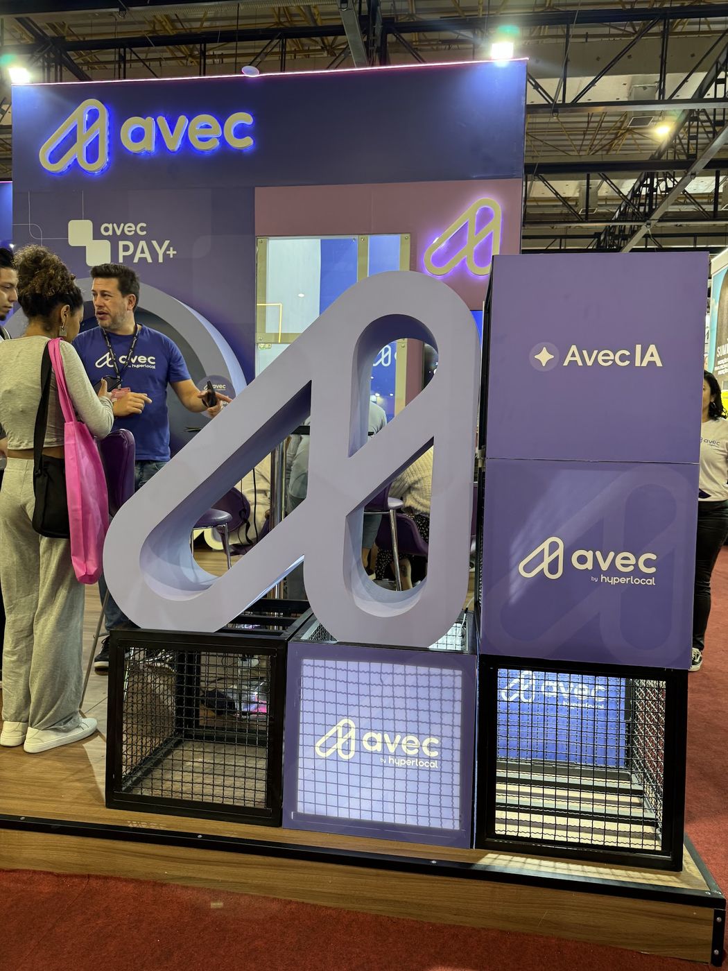 Detalhe de estrutura de stand com logotipo tridimensional, telas e gaiolas decorativas em feira