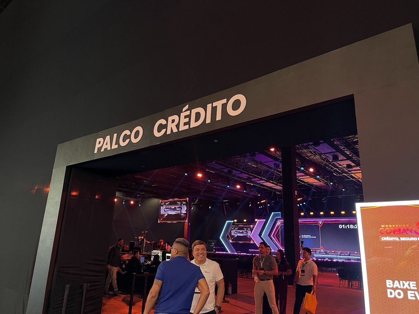 Entrada de evento corporativo com iluminação cênica colorida e visitantes