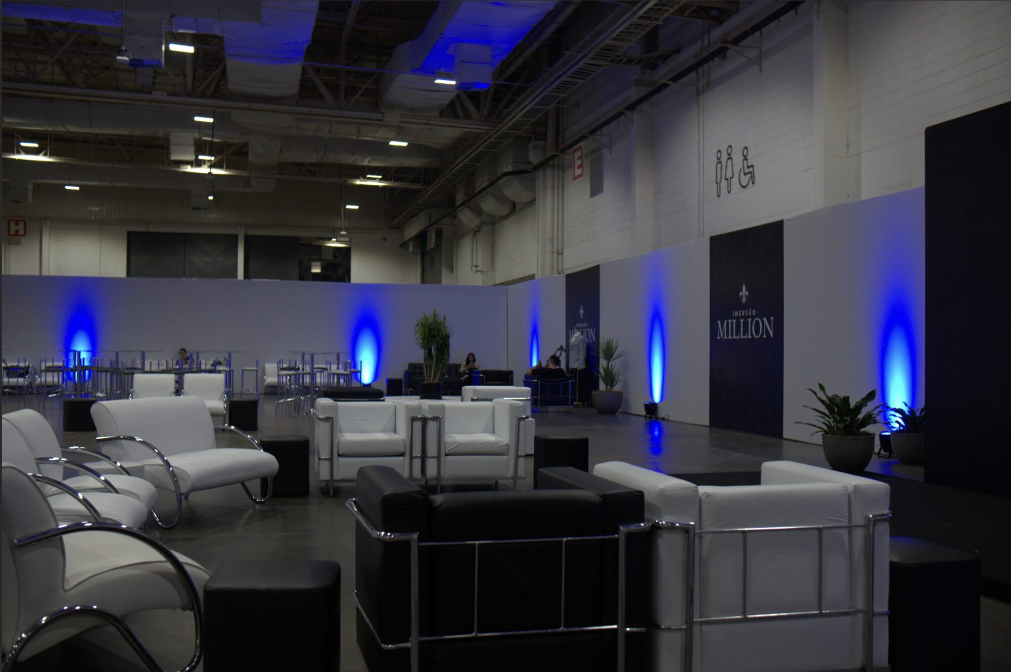 Lounge com iluminação cênica azul em evento corporativo produzido pela Atom Cenografia