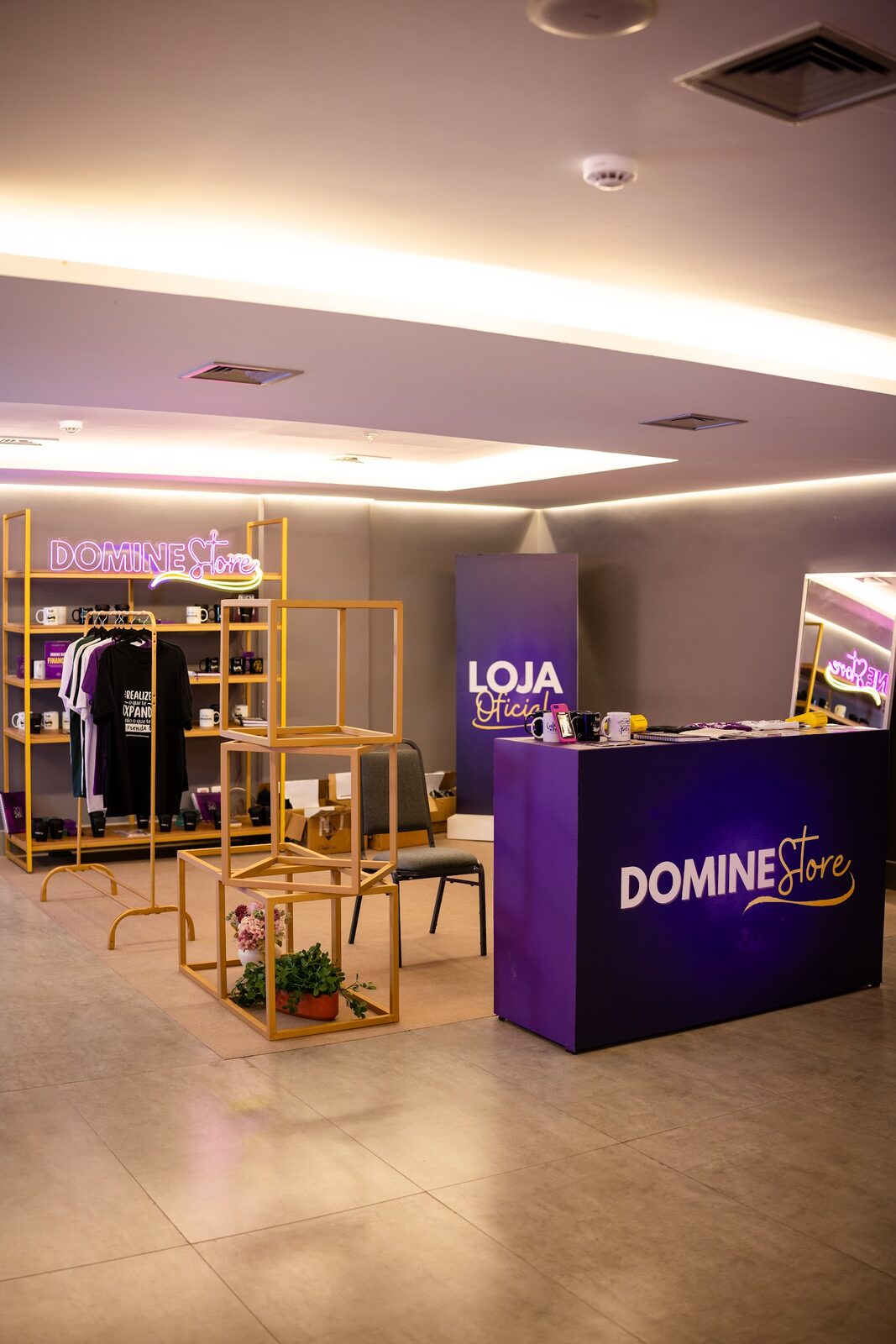 Pop-up store modular com estrutura em cubos de metal, araras e balcão personalizado com identidade visual da marca