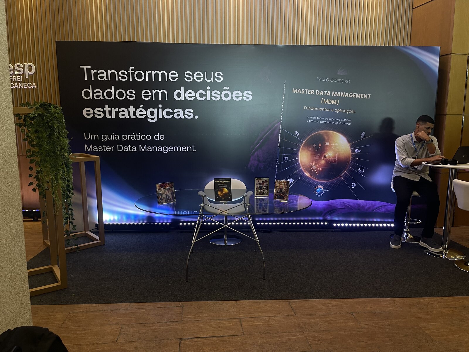 Ponto de fotos do evento Amigos do Cadastro, com perfil de LED azul embutido e mesa de apoio, ambientação produzida pela Atom Cenografia