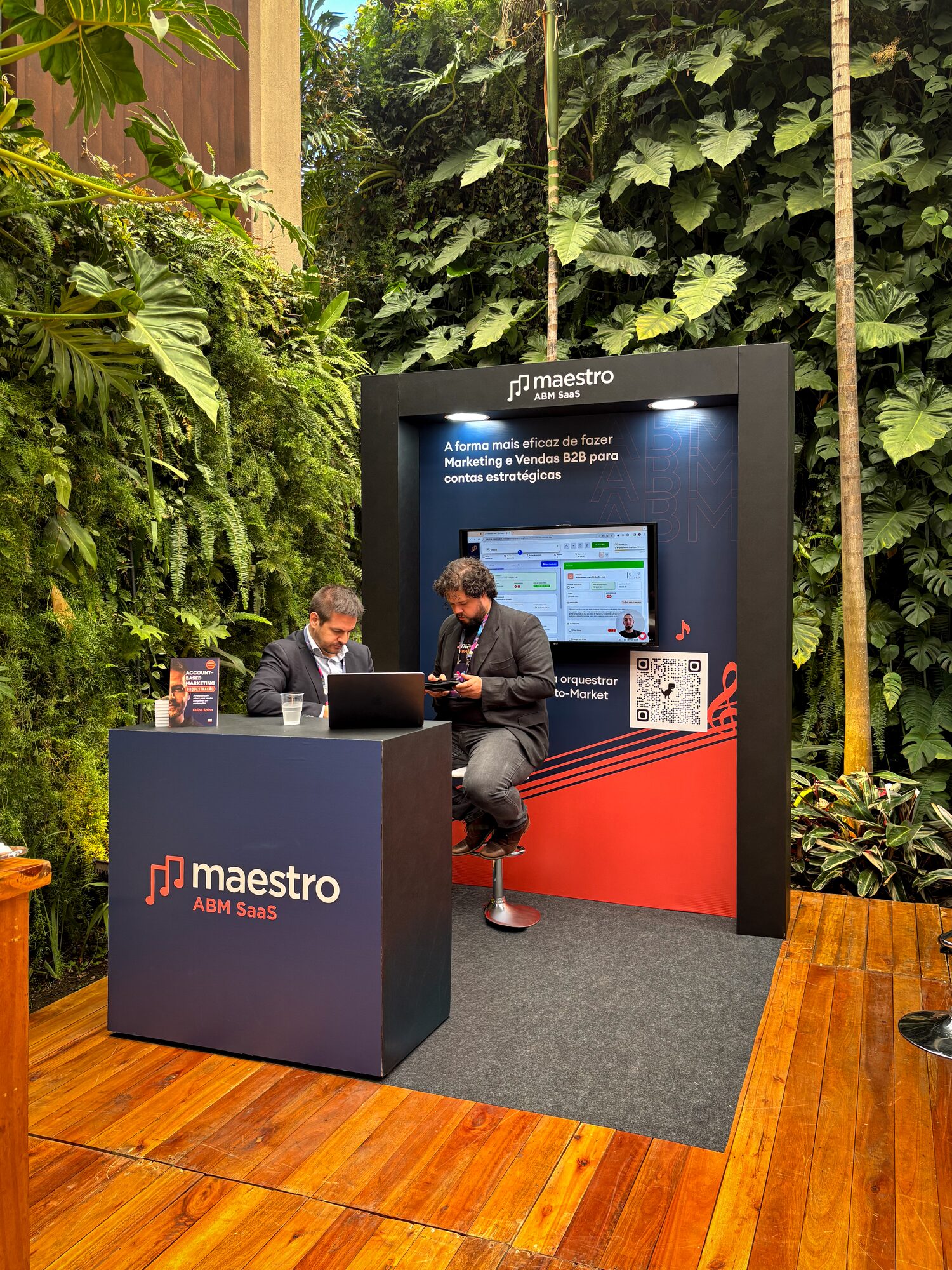Estação de atendimento com pórtico e TV alinhada ao jardim vertical no Cortex Summit 2025, Casa Giardini