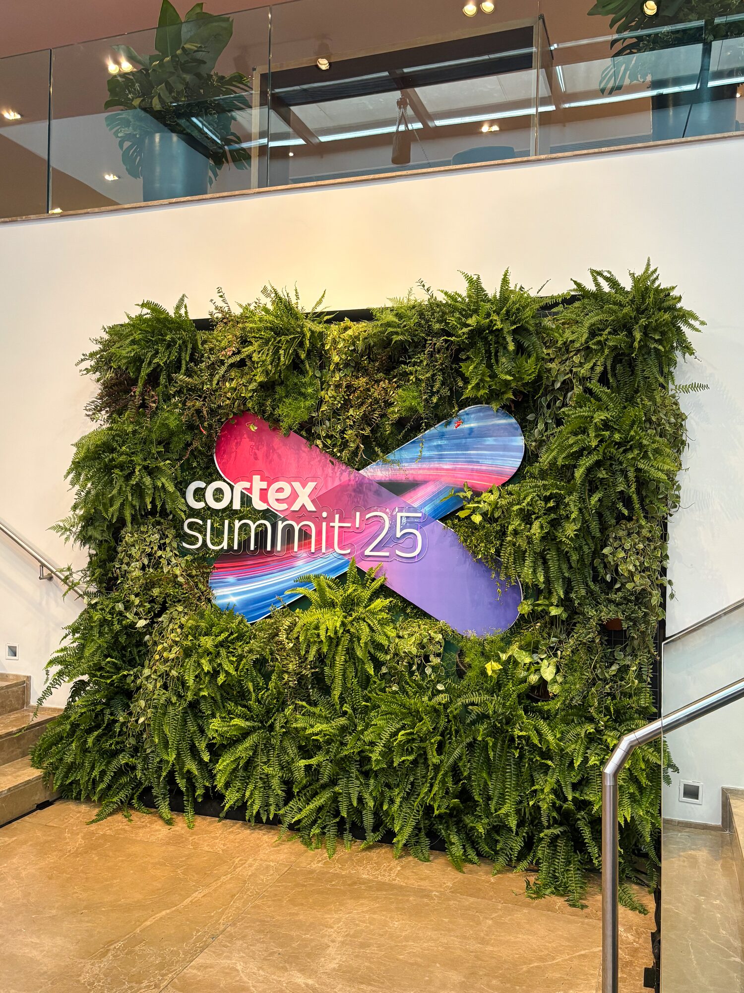 Backdrop em jardim vertical com o logo do Cortex Summit 2025 em recorte, na Casa Giardini