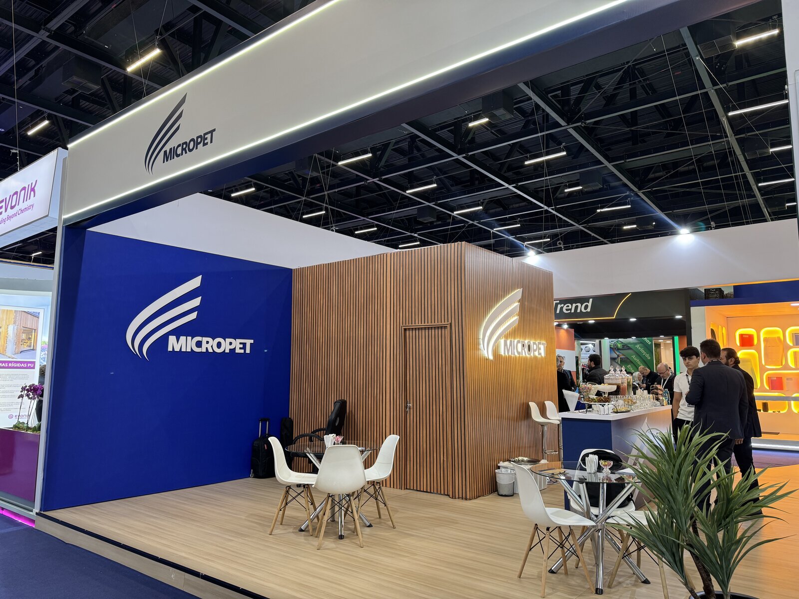 Stand da Micropet na Feiplar & Feipur 2026 com volume em madeira ripada, logo iluminado e área de convivência, montado pela Atom Cenografia