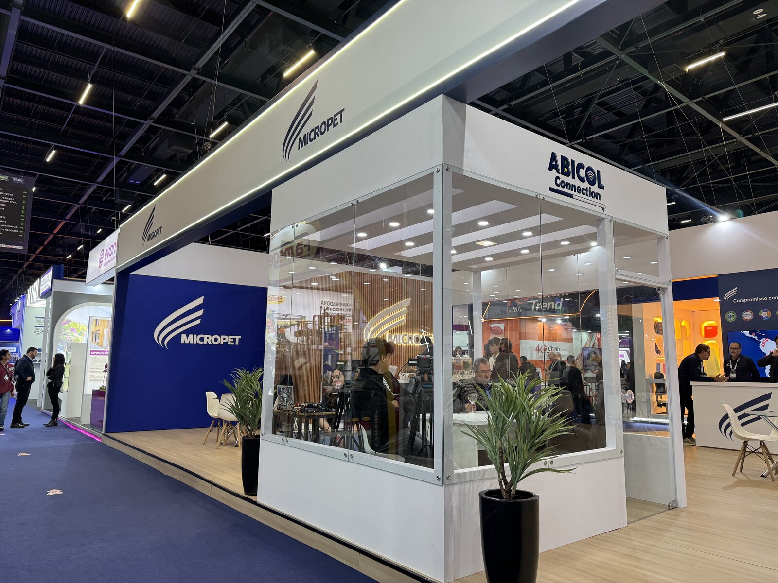 Sala de reunião fechada em vidro dentro do stand da Micropet, com equipe em atendimento